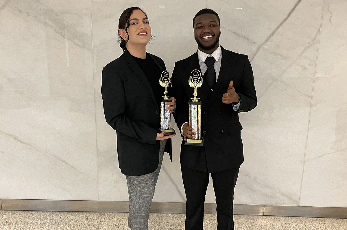 Woman and man standing with trophies